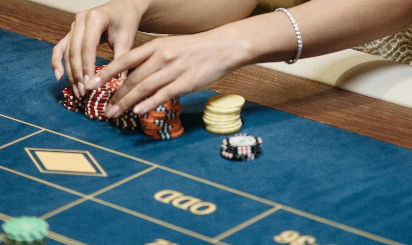Hands stacking casino chips on a blue gaming table