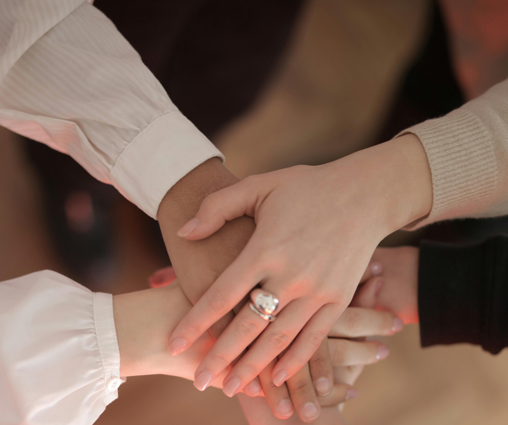 Team members stacking hands to represent trust and long-term relationships in recruitment